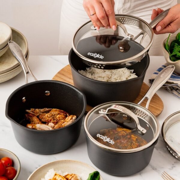 Eaziglide Neverstick3 3 Piece Saucepan Set with glass lids, featuring stacked non-stick saucepans and stainless steel handles.